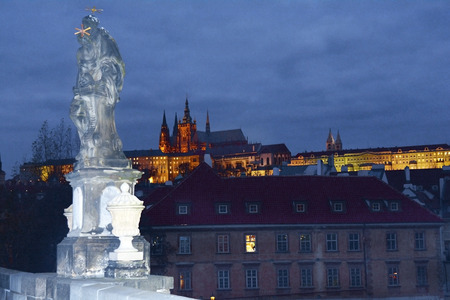Prague, Czech Republic - sculpture on Charles bridge aka Karluv Most and illuminated hradschin - castle - with Saint Vitus cathedralのeditorial素材
