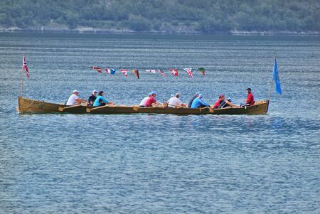 Kaupanger, Norway - June 13th 2009: Unidentified people in rowing boat with different flags on Sognefjordのeditorial素材