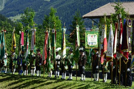 Austria, men with traditional flags and dress by field mass in Tyrolのeditorial素材