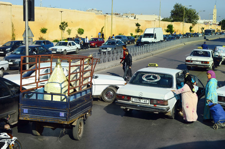 Rabat, Morocco - November 18th 2014: Unidentified woman in traditional kaftan entering a mercedes taxi, usual mode of transport up to 7 peopleのeditorial素材