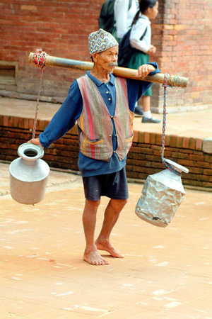 Patan, Nepal - July 14th 2004: Unidentified old man without shoes carrying cans with water, traditional kind of occupationのeditorial素材