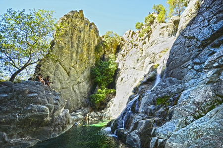 Samothrace, Greece - September 20, 2016: Unidentified couple rest on rock at Xiropotamos waterfall and pondの写真素材