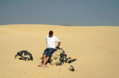 Spain, Canary Island, Fuerteventura, senior on rock in the dunes of El Jable national parkのeditorial素材