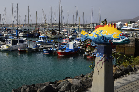 Corralejo,  Spain - March 29, 2017: Fish sculpture and boats in yacht harbor in Furenteventura, Canarxy Islandのeditorial素材