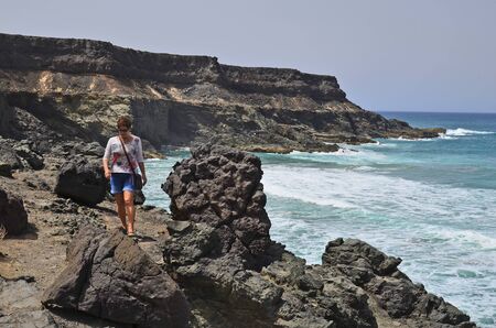 Fuerteventura, Spain - April 01, 2017: Unidentified woman walking along rocky coast in El Puerte de Los Molinos,のeditorial素材