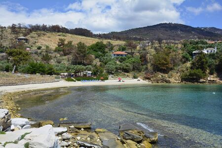 Aliki, Greece - June 10, 2017: Unidentified people on tiny beach and forest damaged from forest fire 2016 on Thassos islandのeditorial素材