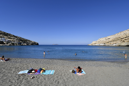 Matala, Greece - October 07, 2018: Unidentified people on sandy beach with Paximadia islands in backgroundのeditorial素材
