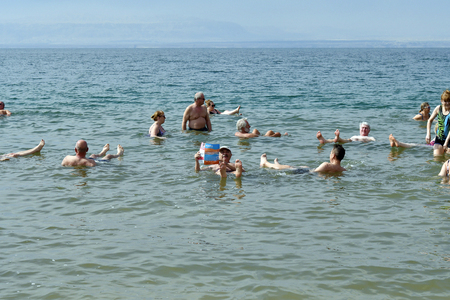 Dead Sea, Jordan - March 05, 2019: Unidentified people enjoy swim in Dead Sea, a salt lake 400m below sea level, water and mud is used for therapeutic and cosmetic treatments, people are unsinkable because for the degree of the high salinityのeditorial素材