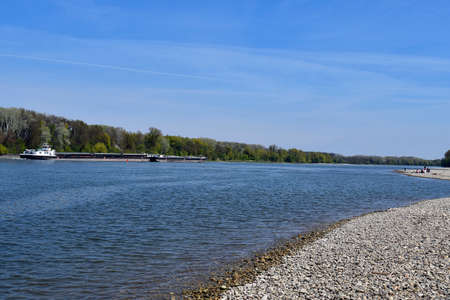 Austria, barge on the Danube river in the Donau-Auen National Park in Lower Austria and group of people on gravel shoreの写真素材