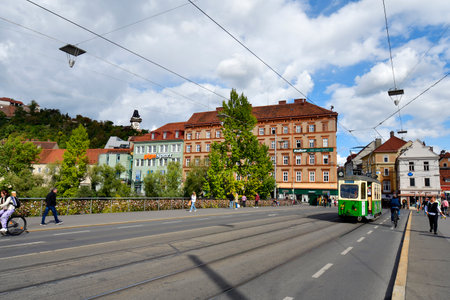 Graz, Austria - September 22, 2022: Nostalgic tram on Archduke Johann Bridge with the landmark Uhrturm aka Clock Tower on castle hillのeditorial素材