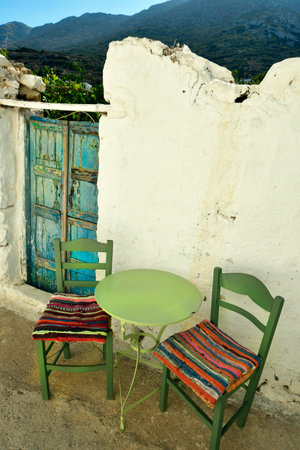 Greece - Green seating with colorful cushions and an old blue wooden gate in the mountain village of Lagkada on Amorgos island, a wonderful Cycladic island in the Aegean Seaの写真素材
