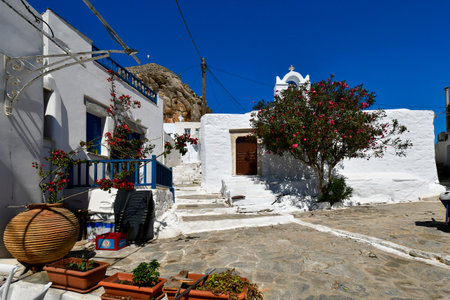 Amorgos, Greece - September 11, 2025: Street paved with natural stone, with steps leading up to a chapel and the castle rock in the background.の写真素材