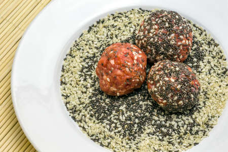Raw meatballs with chia seeds and sesame on a plate