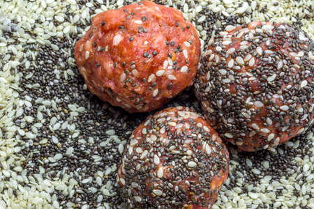Raw meatballs with chia seeds and sesame on a plateの写真素材