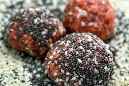 Raw meatballs with chia seeds and sesame on a plateの写真素材