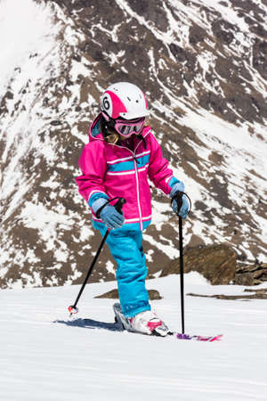 Girl on skis in soft snow on a sunny day in the mountains, on a steep slope の写真素材