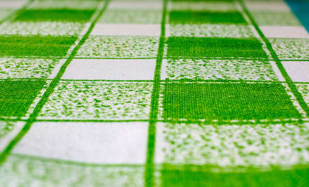 Green and white tablecloth fabric at an angle with a focus in the middleの写真素材