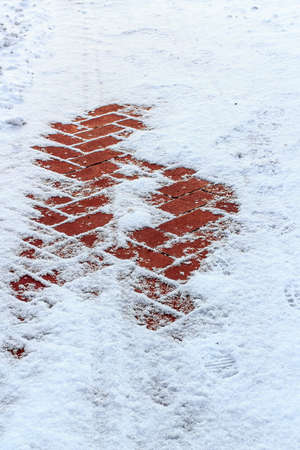 lane paved with red tiles covered with snow  Focus on foreground