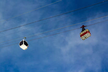 Old Aerial tramways and a new gondola ski lift in the mountains on the background of the cloudy sky on a sunny day の写真素材