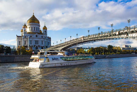 Embankment of the Moskva River 25 September, 2013  Tourist boat on the river under the bridge with a view of the Christ the Saviour Cathedral and Patriarshy bridge on a sunny day on a background of the blue sky with cumulus cloudsのeditorial素材