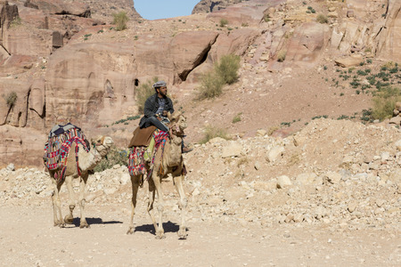 Petra, Jordan - December 25th, 2015: Bedouin man riding a camel in the ancient Nabatean city of Petra, Jordanのeditorial素材
