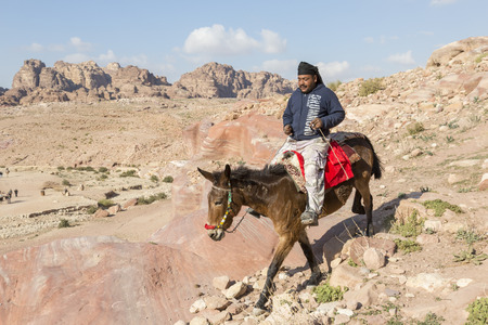 Petra, Jordan - December 24th, 2015: Bedouin man riding a horse in the ancient Nabatean city of Petra, Jordanのeditorial素材