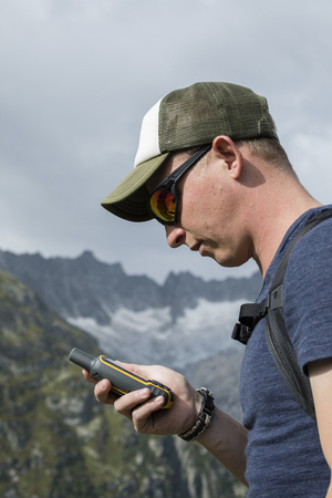 Alpinist is oriented with a GPS device in the terrainの写真素材