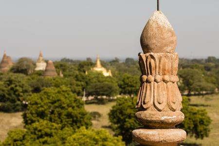 Architectural detail of a pagoda in the foreground and the pagoda field of Bagan out of focus in background, Myanmarの写真素材