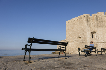 Dubrovnik, Croatia, July 20 2017: A local man sits on a bench in the morning light and in the background the mighty city wall of Dubvronikのeditorial素材