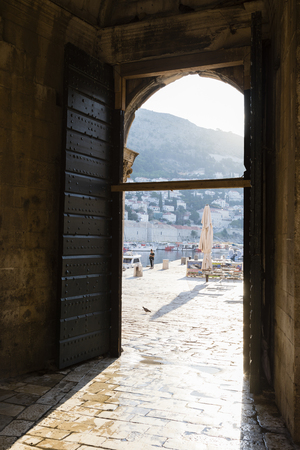 Dubrovnik, Croatia, July 20 2017: View through a city gate on the boat harbor of Dubvronik which is illuminated by the morning sunのeditorial素材