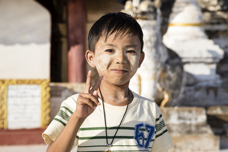Bagan, Myanmar, December 29, 2017:  Handsome boy with Tanaka in the face makes the Victory sign in Bagan, Myanmarのeditorial素材