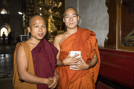 Bagan, Myanmar, December 29, 2017:  Portrait of two Buddhist monks in the Ananda Pagoda in Bagan. A monk holds a tablet in his hand.のeditorial素材