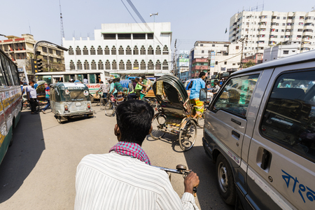 Dhaka, Bangladesh, February 24 2017: Driving a trishaw in the chaotic traffic of Dhaka from the perspective of the passenger with the driver in the foreground, Bangladeshのeditorial素材