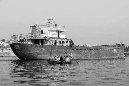 Dhaka, Bangladesh, February 24 2017: Wooden taxi boat with passengers and a cargo ship in background on the Buriganga River in Dhaka Bangladeshのeditorial素材