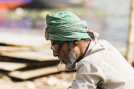 Dhaka, Bangladesh, February 24 2017: Worker on a ship dock in Dhaka Bangladesh smokes a cigarette