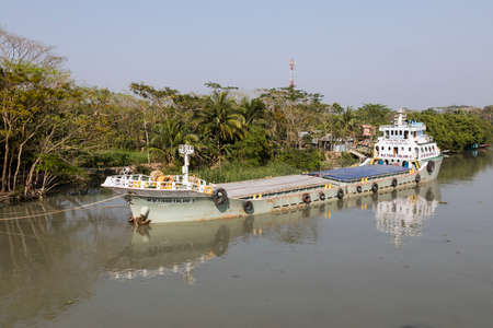 Khulna, Bangladesh, March 1 2017: Cargo ship has anchored a riverside to pick up goodsのeditorial素材