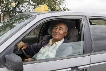 Karakol, Kyrgystan, August 12 2018: Friendly Taxi driver in his old rusty car in Karakol City, Kyrgyzstanのeditorial素材