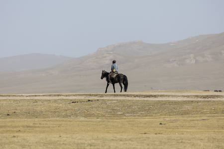 Song Kul, Kyrgyzstan, August 8 2018: Man rides leisurely on a horse at Song Kul Lake in Kyrgyzstanのeditorial素材
