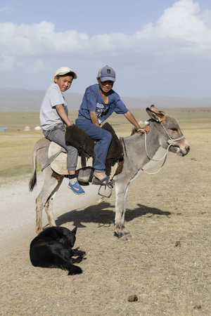Song Kul, Kyrgyzstan, August 8 2018: Two boys and a donkey at Song Kul lake in Kyrgyzstanのeditorial素材