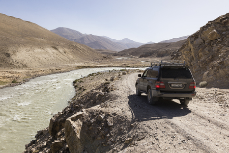 Langar, Tajikistan, August 23 2018: Off-road car is waiting on the Pamir Highway on the Pamir River. On the left of the river is Afghanistan and on the right Tajikistanのeditorial素材