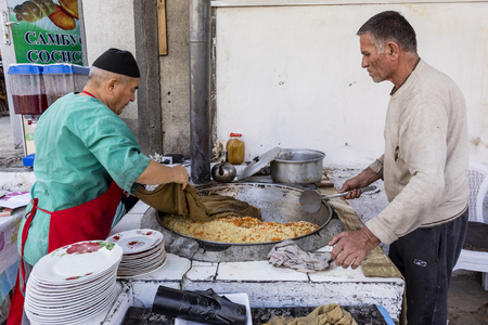 Khorog, Tajikistan August 25 2018: Two sellers are cooking a rice dish in a big pancake at the market in Khorog in Tajikistanのeditorial素材