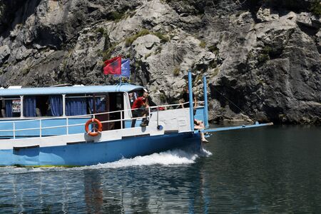 Koman, Albania, July 7 2019: A tourist boat overtakes the car ferry on Komani Lake in the dinaric alps of Albaniaのeditorial素材