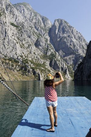 Koman, Albania, July 7 2019: A tourist takes a picture of the boat ramp from the beautiful landscape of mountains and green forests on a boat trip on the Komani lake in the dinaric alps of Albaniaのeditorial素材