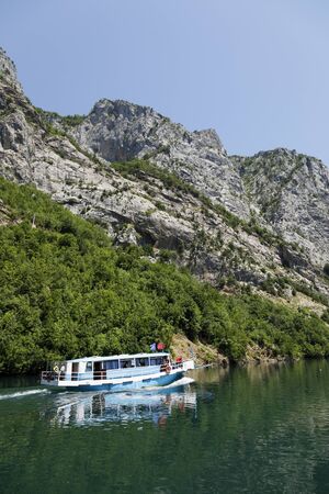 Koman, Albania, July 7 2019: A tourist boat overtakes the car ferry on Komani Lake in the dinaric alps of Albaniaのeditorial素材