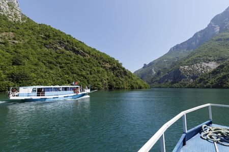 Koman, Albania, July 7 2019: A tourist boat overtakes the car ferry on Komani Lake in the dinaric alps of Albaniaのeditorial素材