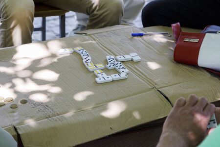 Berat, Albania, July 9 2019: Old men play the game domino in Berat in the shade of trees. Close-up of dominoesのeditorial素材