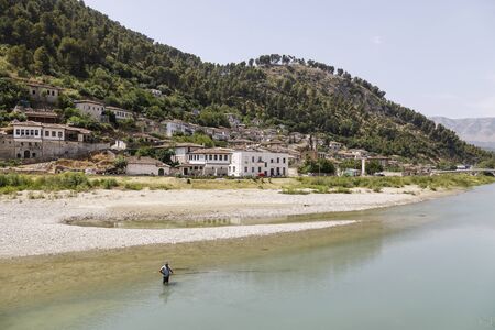 Berat, Albania, July 9 2019: A fisherman is fishing in a river that flows through Beratのeditorial素材