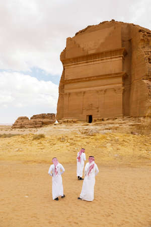 AlUla, Saudi Arabia, February 19 2020: Three Saudis stand in front of the tomb of Lihyan son of Kuza, known as Qasr AlFarid, the most iconic tomb in AlUla in the region of Mada'in Saleh, Saudi Arabiaのeditorial素材
