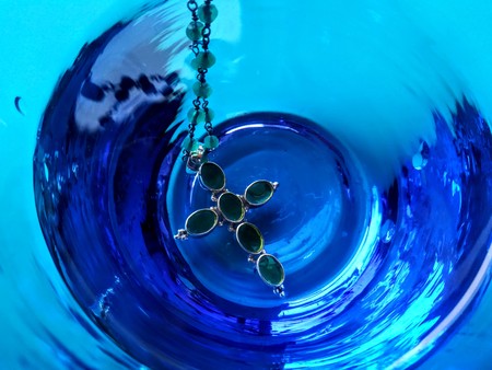 cross jewel pendant in a blue glass beakerの写真素材