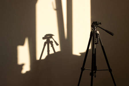 tripod through the window illuminated by the sunの写真素材